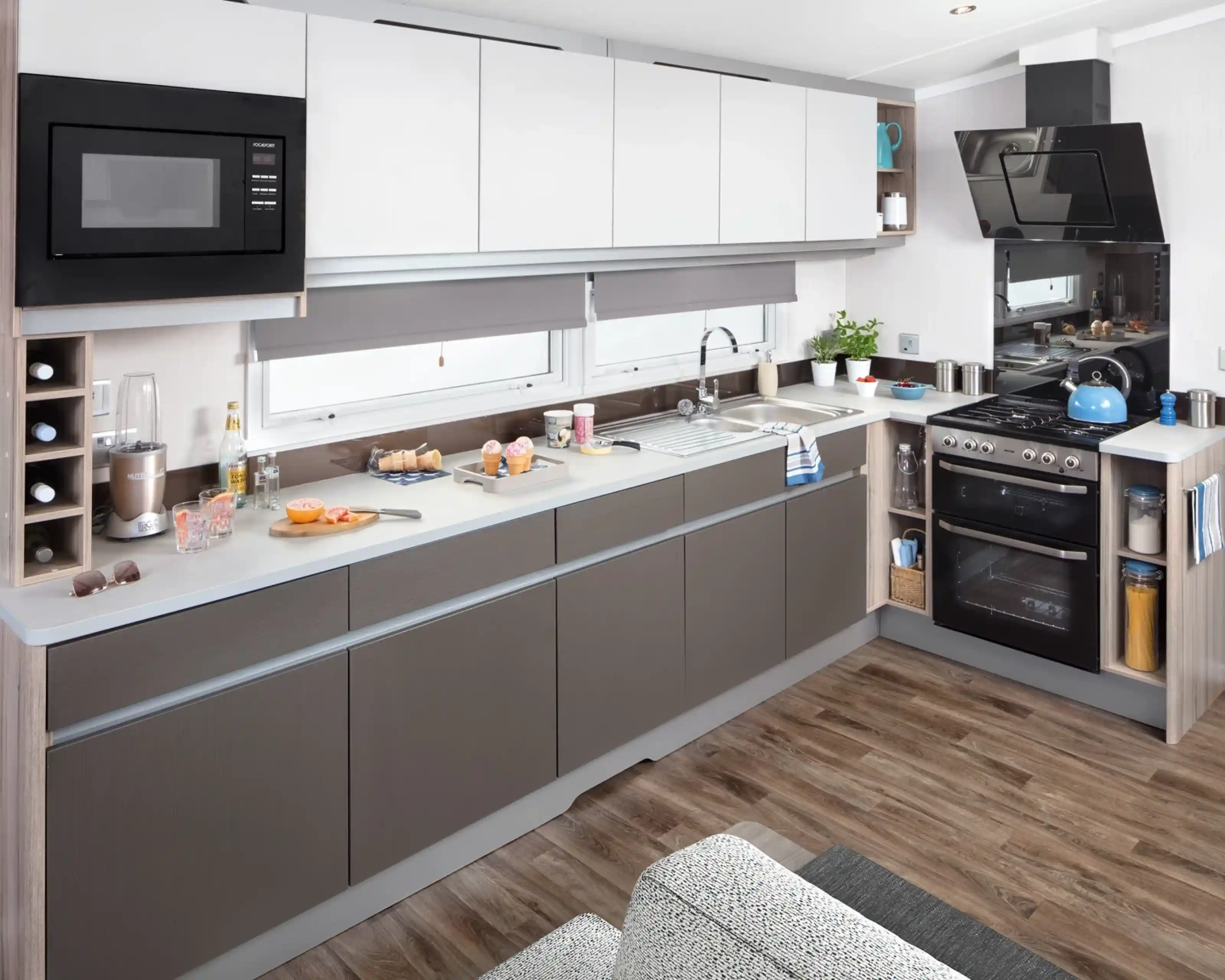 Modern kitchen with white and grey cabinets, stainless steel appliances, and hardwood floors.