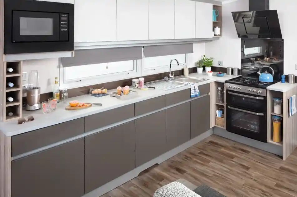 Modern kitchen with white and grey cabinets, stainless steel appliances, and hardwood floors.