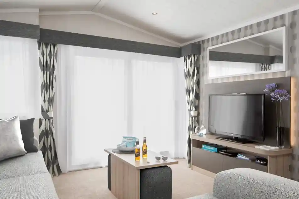 Modern living room with grey sectional sofa, coffee table with drinks, and TV entertainment centre.