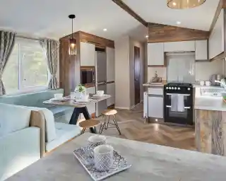 A spacious kitchen and dining room area featuring a comfortable couch and a table, with modern cabinetry, countertops, and home appliances. The space includes hardwood laminate flooring and is designed with an open floor plan.