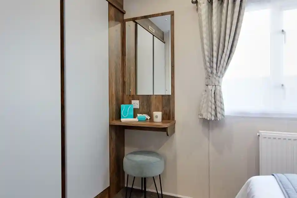 A room featuring a mirror on the wall with built-in small shelf table below  and double wardrobe.