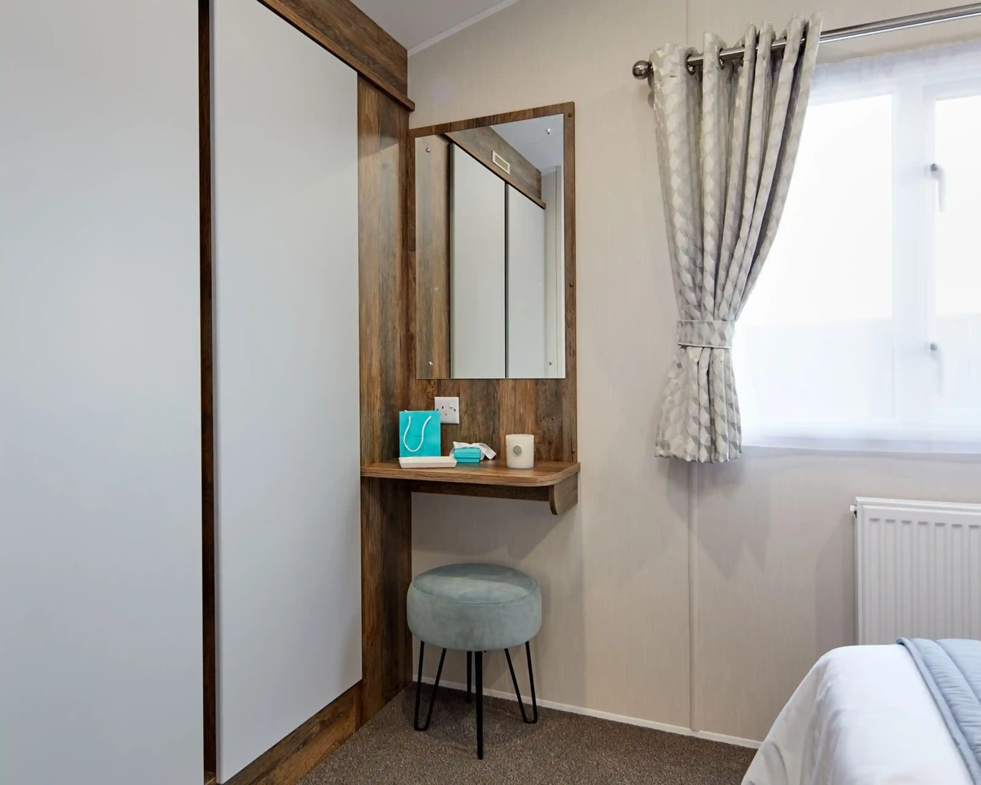 A room featuring a mirror on the wall with built-in small shelf table below  and double wardrobe.