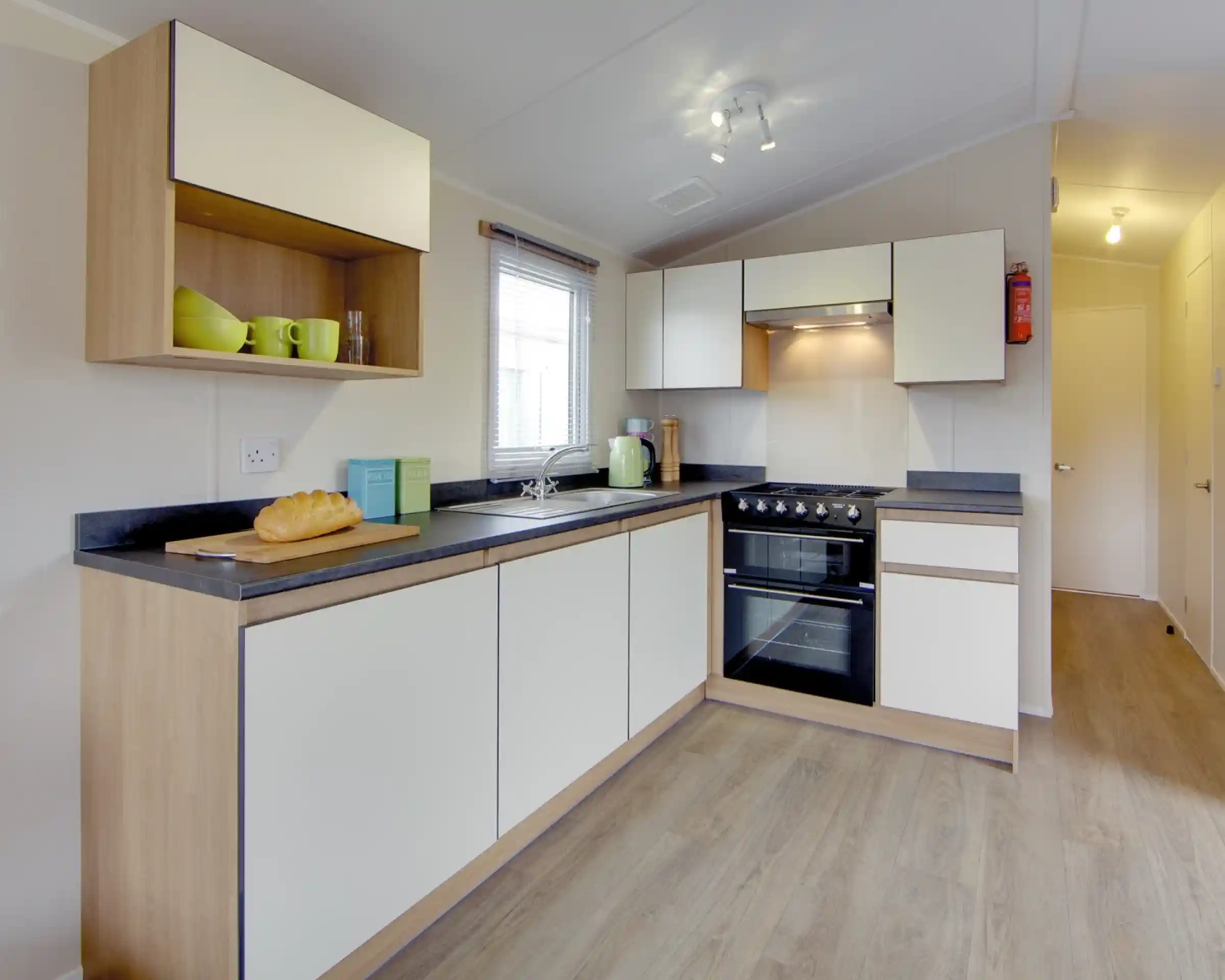 Modern kitchen with white cabinets, wood accents, stainless steel appliances, and a loaf of bread on the counter.