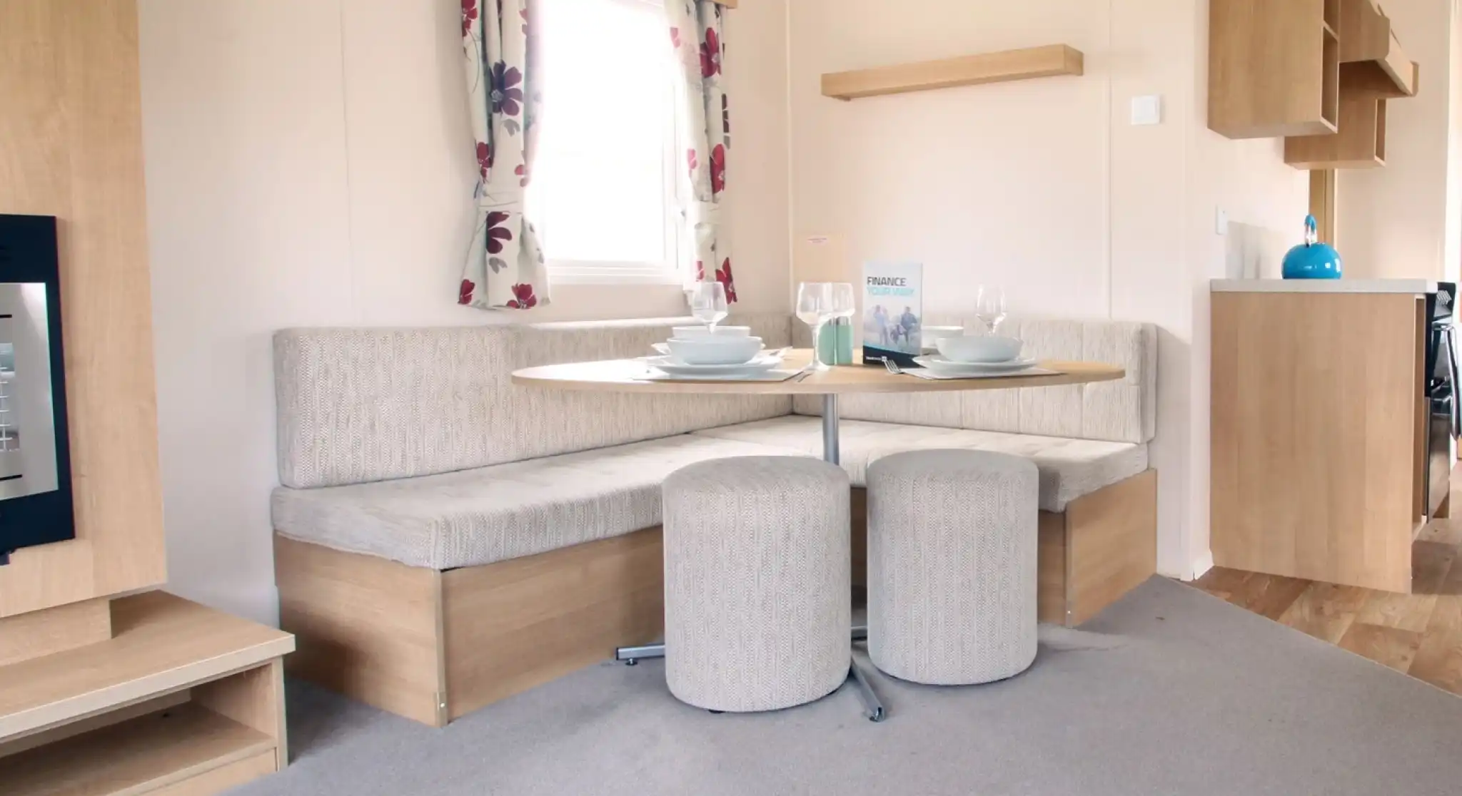 A dining area with L-shaped built-in corner cushioned seating and two stools with oval dining table.