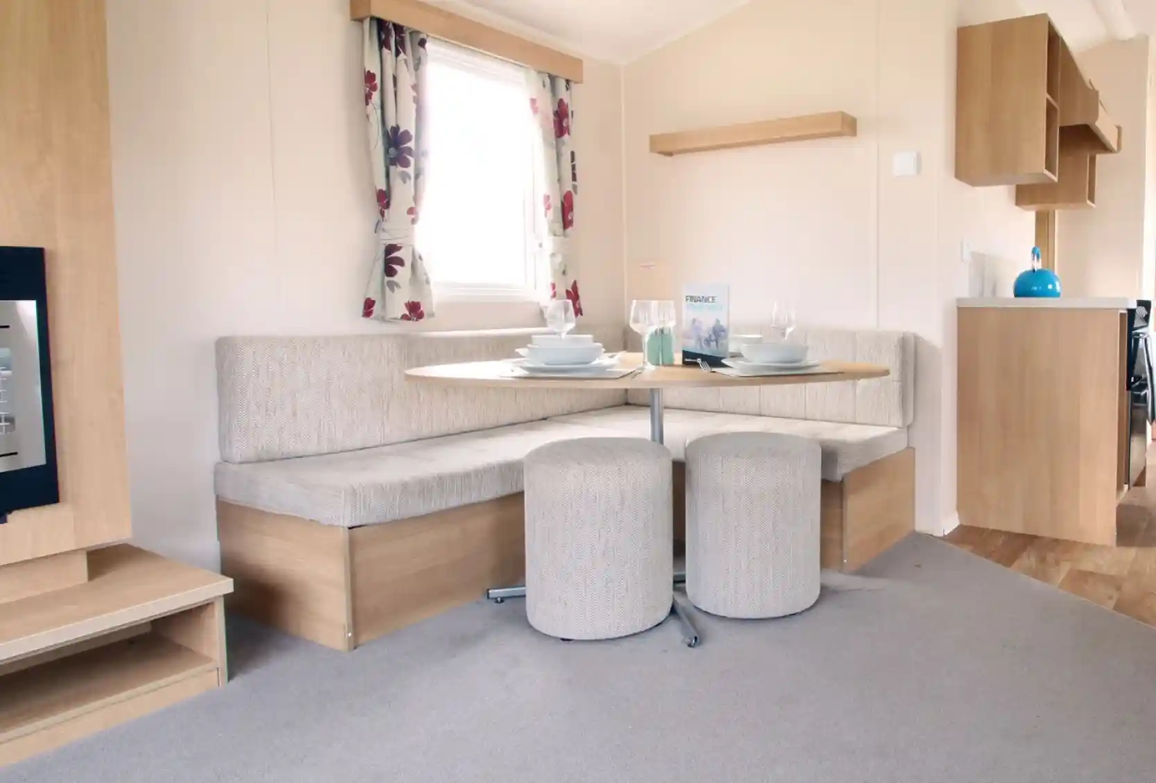 A dining area with L-shaped built-in corner cushioned seating and two stools with oval dining table.
