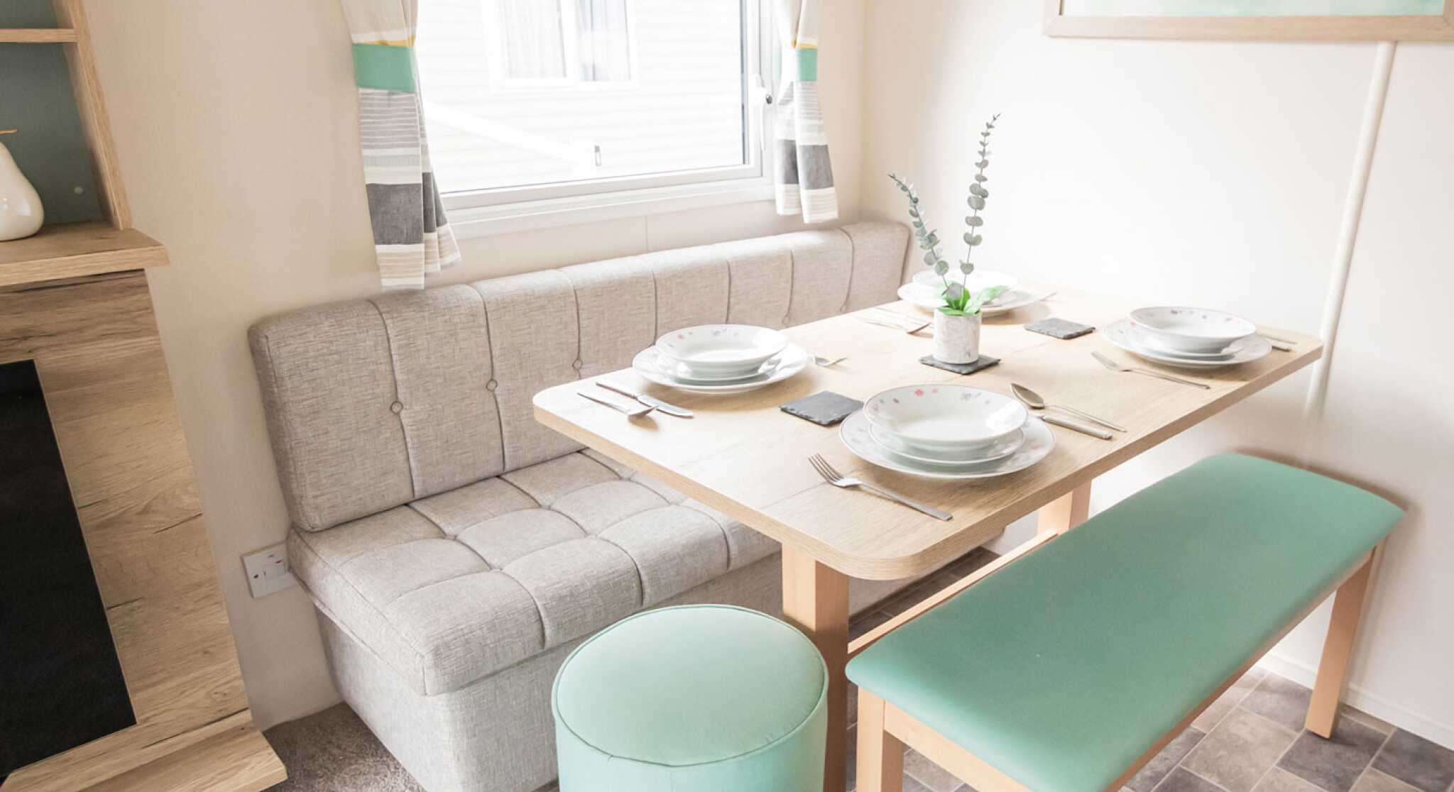 A small dining area featuring a dining table, padded bench seats and a stool.