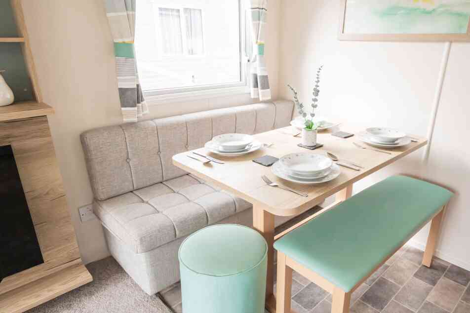A small dining area featuring a dining table, padded bench seats and a stool.