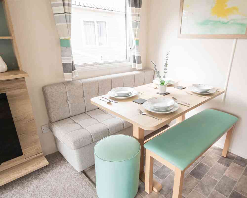 A small dining area featuring a dining table, padded bench seats and a stool.