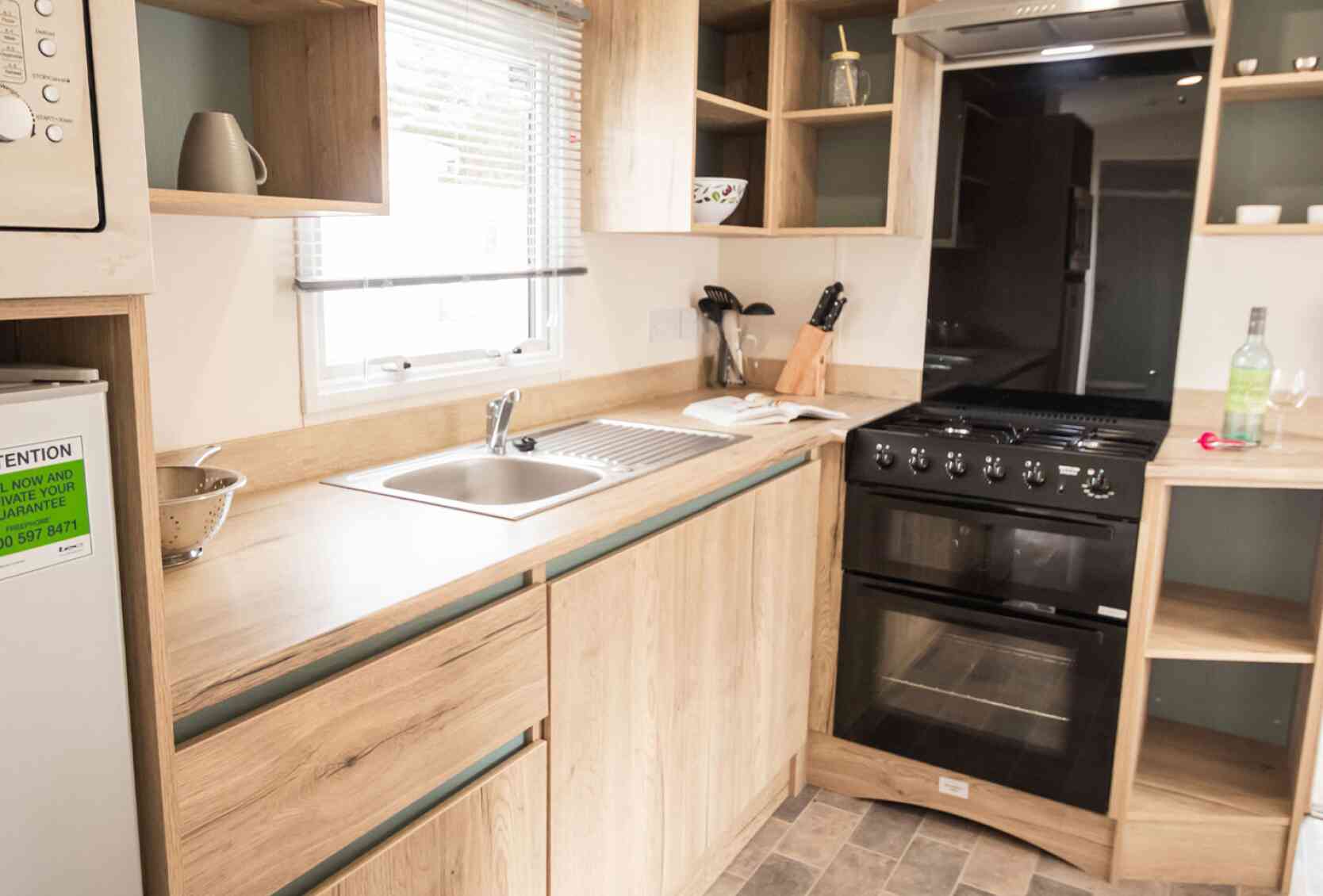 A well-equipped modern kitchen displaying a stove, oven, sink and refrigerator, highlighting essential cooking appliances.