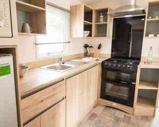 A well-equipped modern kitchen displaying a stove, oven, sink and refrigerator, highlighting essential cooking appliances.