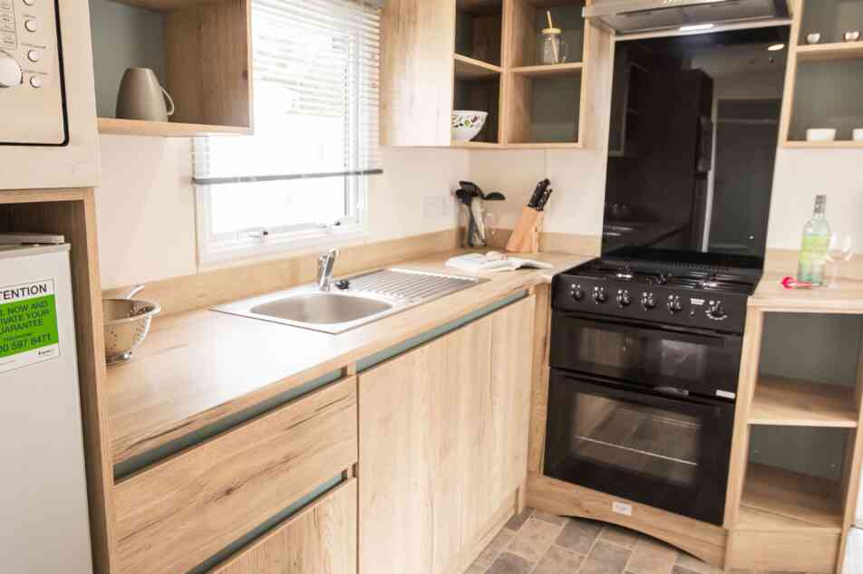 A well-equipped modern kitchen displaying a stove, oven, sink and refrigerator, highlighting essential cooking appliances.