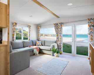 A bright living room with a couch, coffee table, and a window that offers a scenic beach view.
