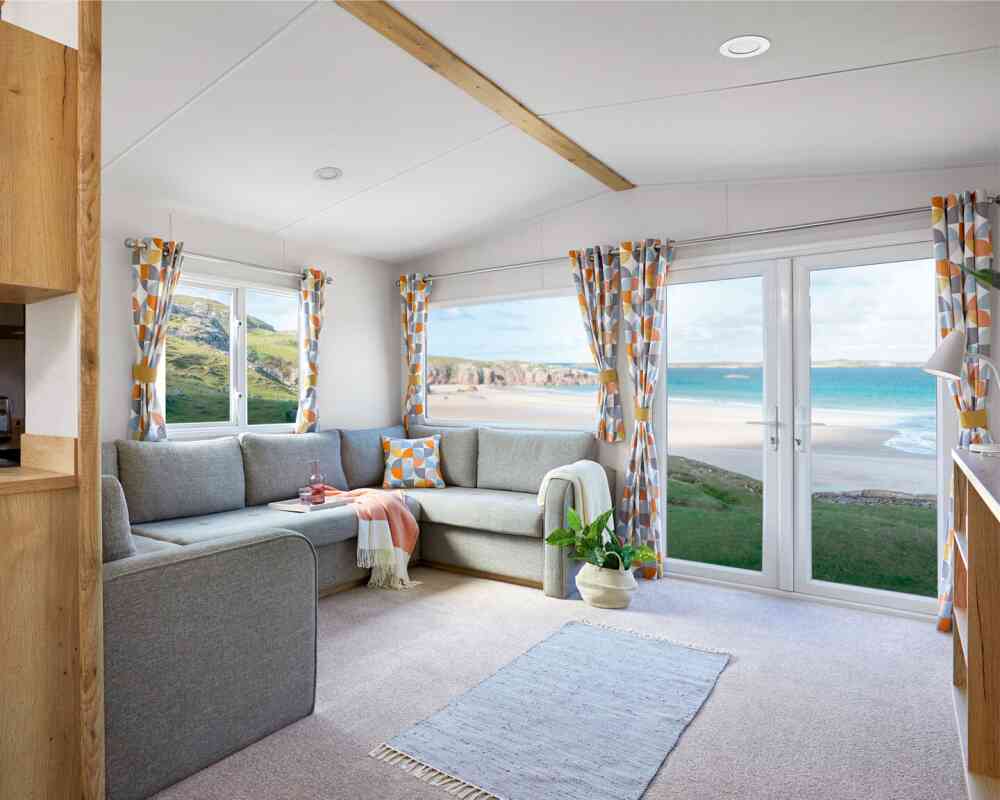 A bright living room with a couch, coffee table, and a window that offers a scenic beach view.