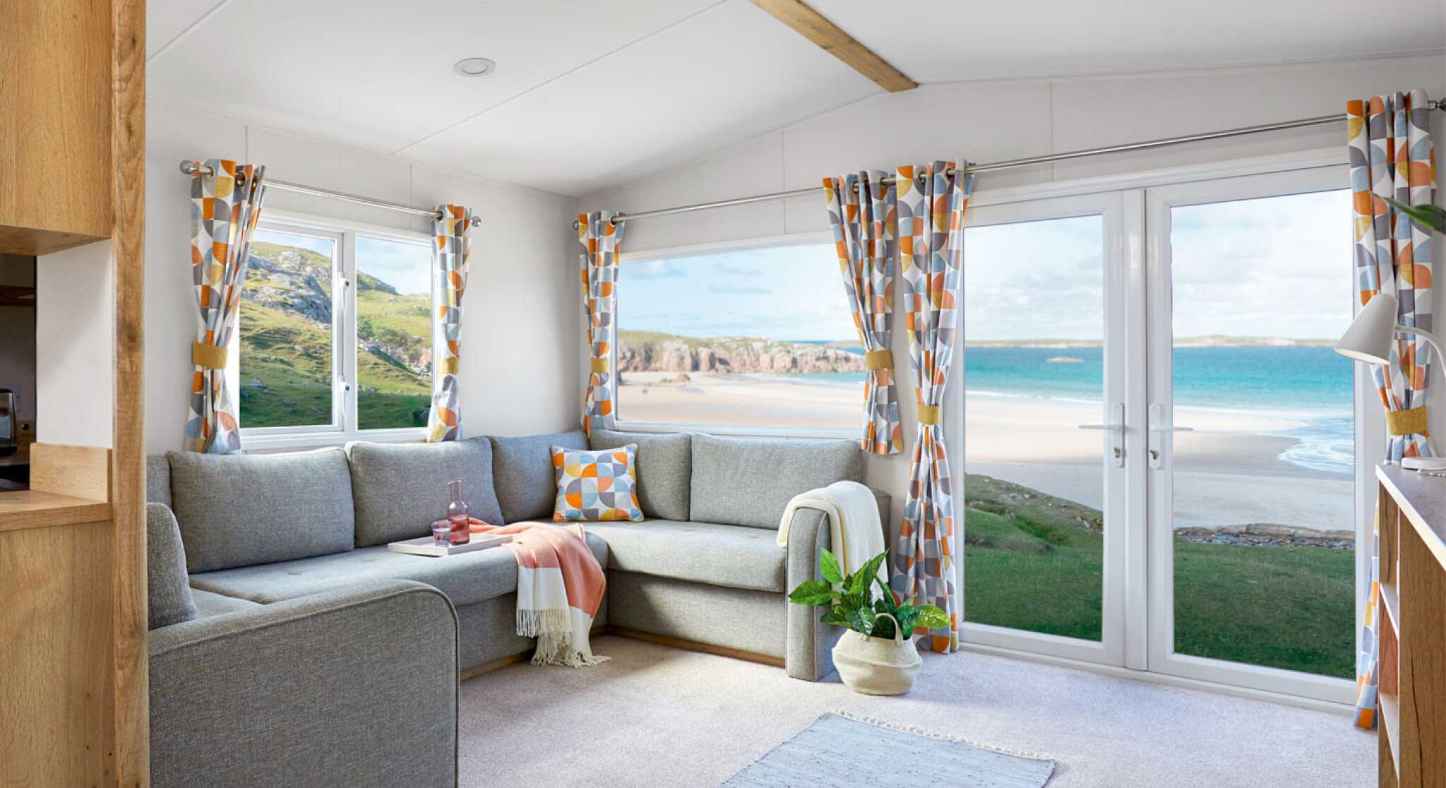 A bright living room with a couch, coffee table, and a window that offers a scenic beach view.