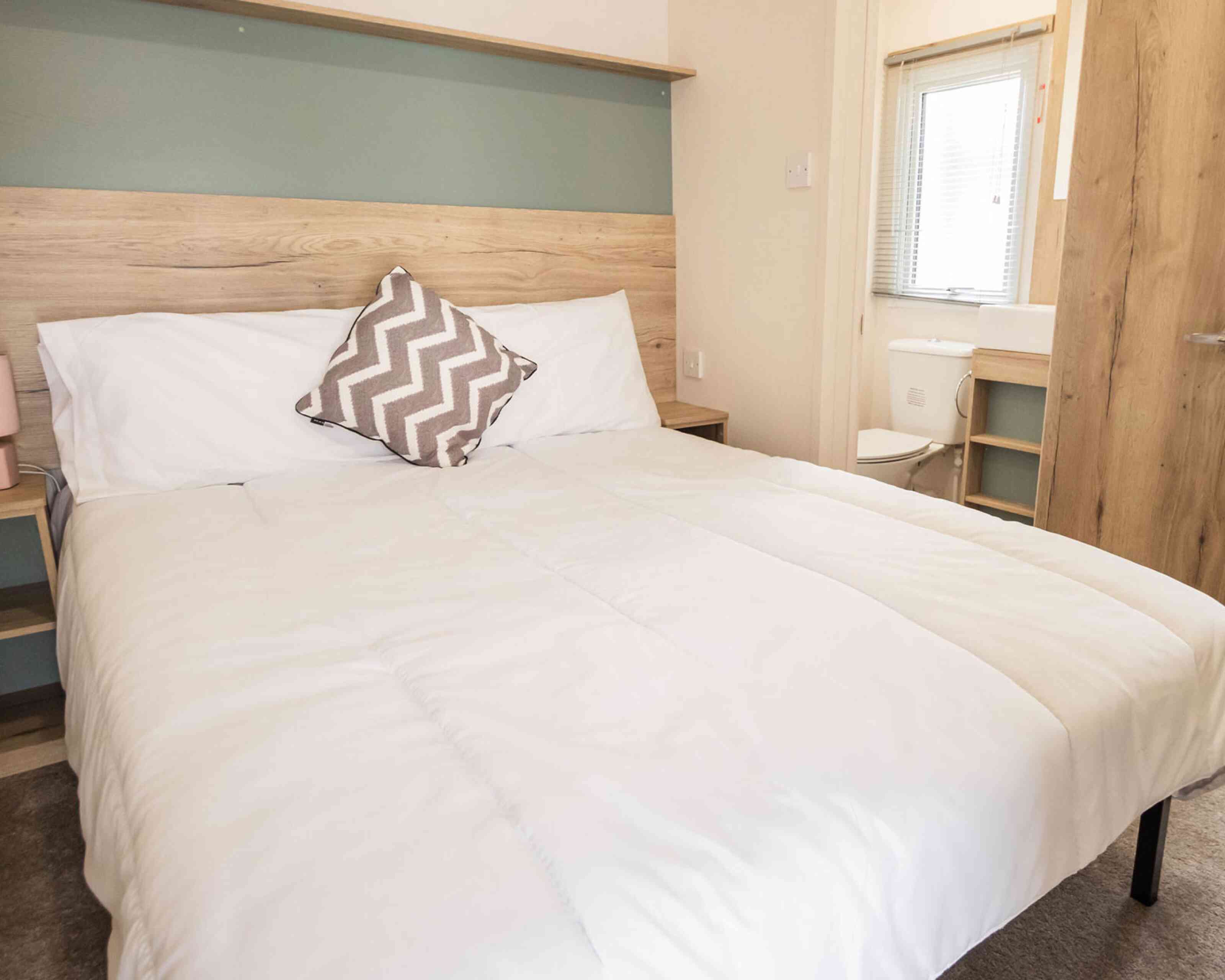 A bedroom featuring a double bed adorned with crisp white sheets and fluffy pillows.