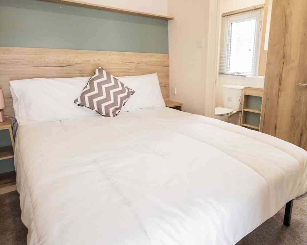 A bedroom featuring a double bed adorned with crisp white sheets and fluffy pillows.