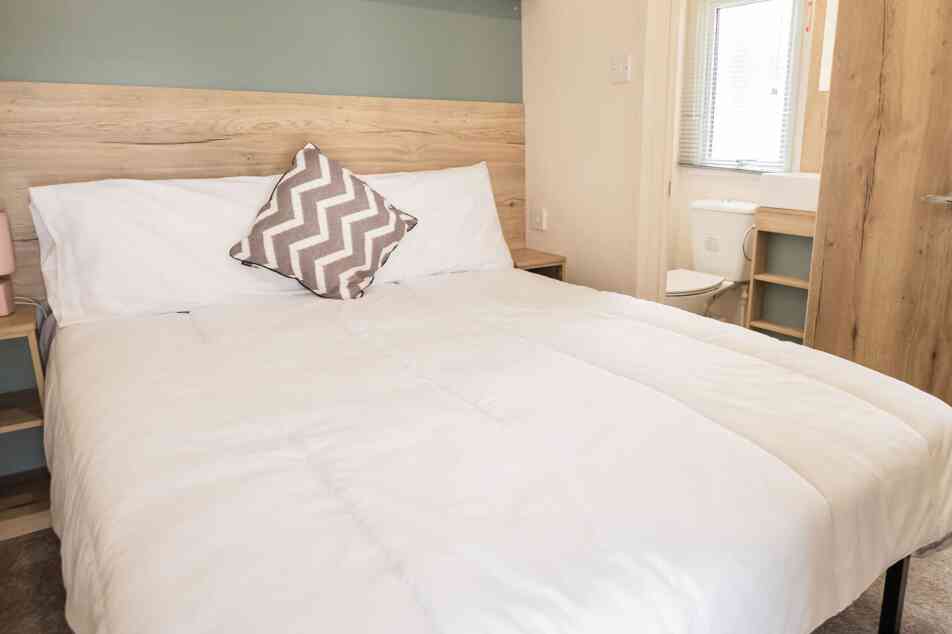 A bedroom featuring a double bed adorned with crisp white sheets and fluffy pillows.