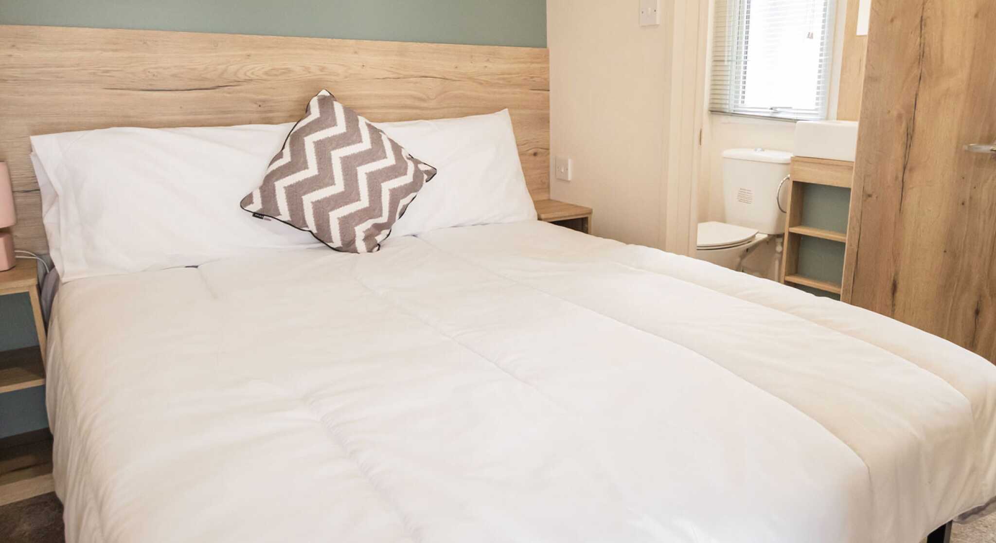 A bedroom featuring a double bed adorned with crisp white sheets and fluffy pillows.