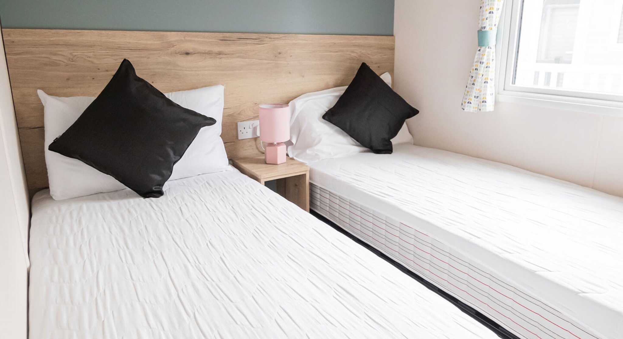 Two twin beds arranged in a small room, complemented by a window that brightens the space.