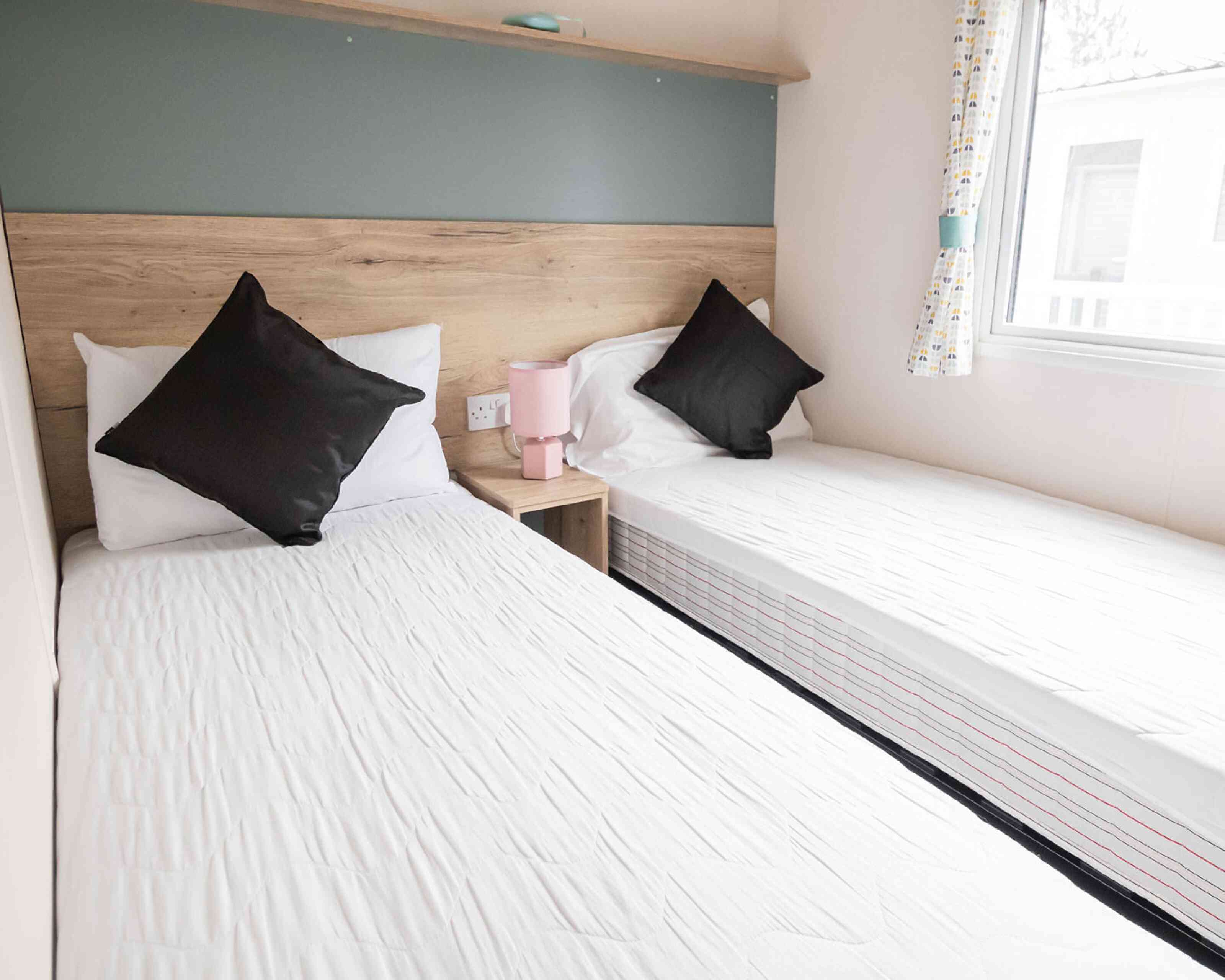 Two twin beds arranged in a small room, complemented by a window that brightens the space.