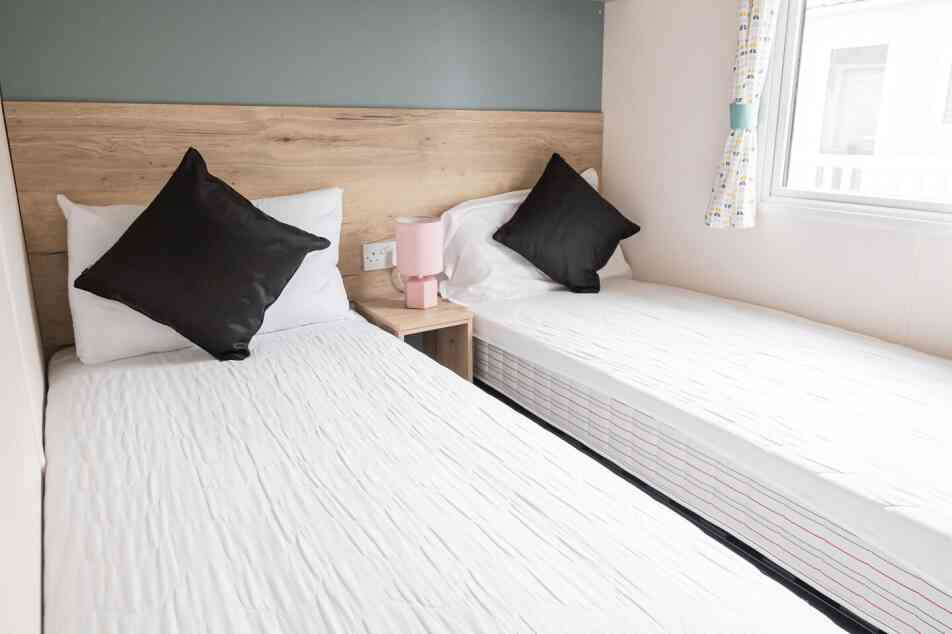 Two twin beds arranged in a small room, complemented by a window that brightens the space.