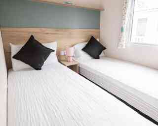 Two twin beds arranged in a small room, complemented by a window that brightens the space.