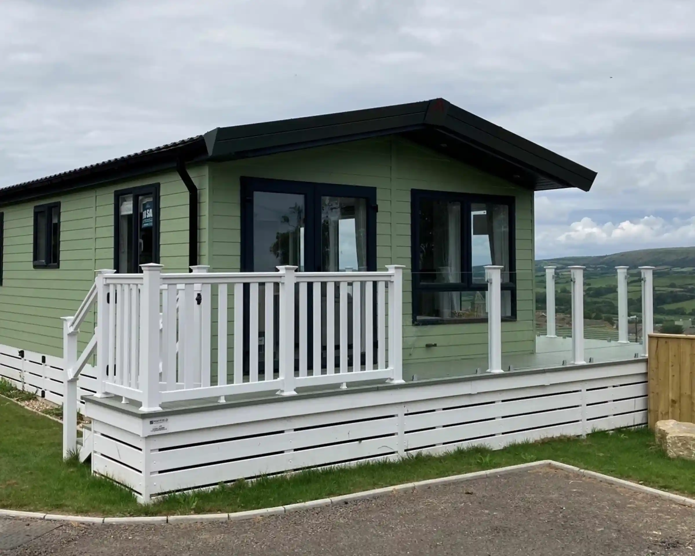 Exterior of the Atlas Lilac Lodge at Swanage Coastal Park with decking and glass balustrade to make the most of the views.
