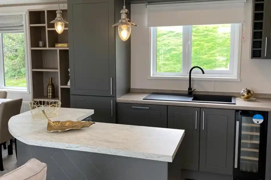 Stylish kitchen in the Atlas Lilac Lodge with grey cabinetry, marble-style countertops and peninsular breakfast bar.