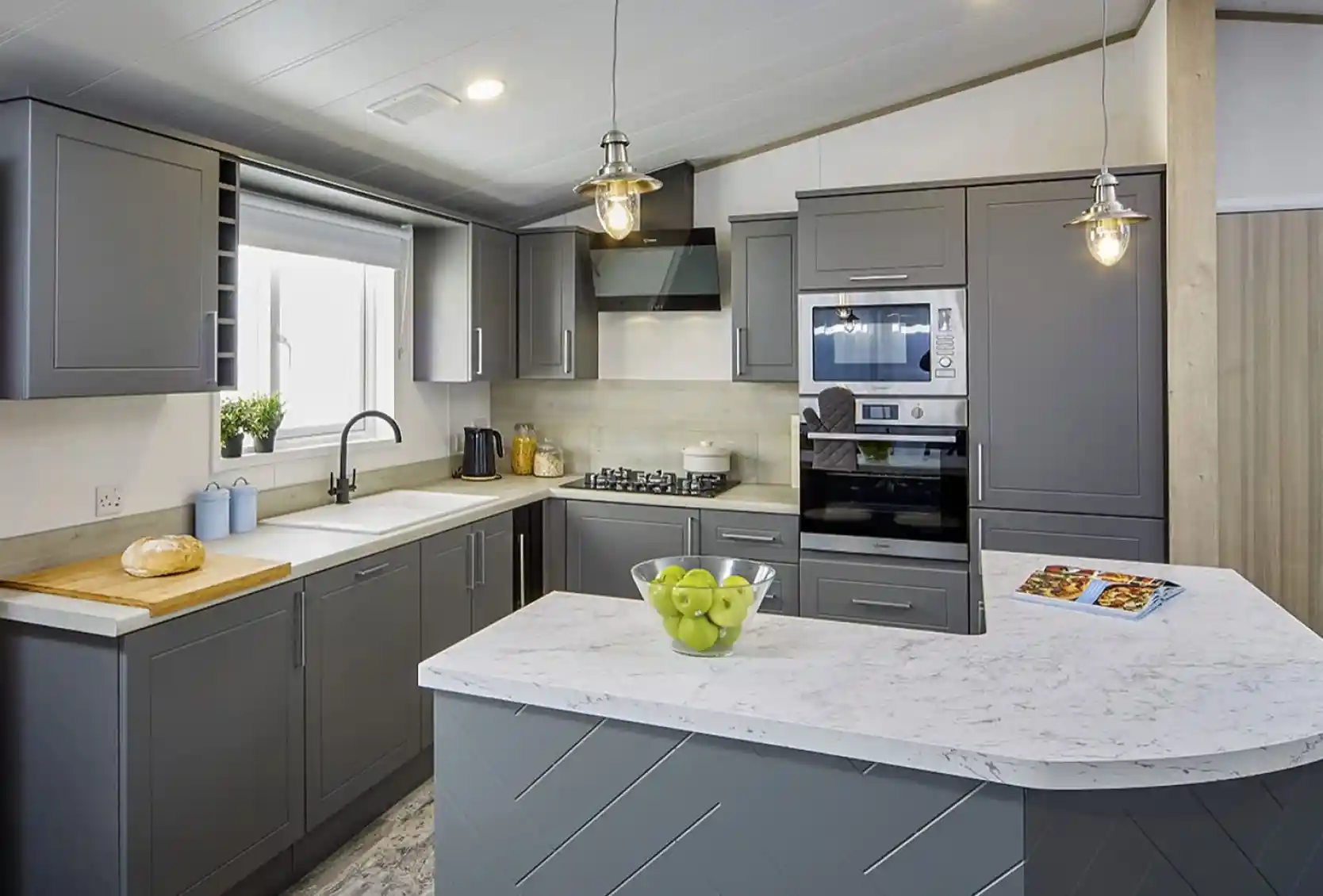 Modern kitchen in the Atlas Lilac Lodge with grey cabinetry, marble-style countertops, built-in oven, and peninsula breakfast bar.