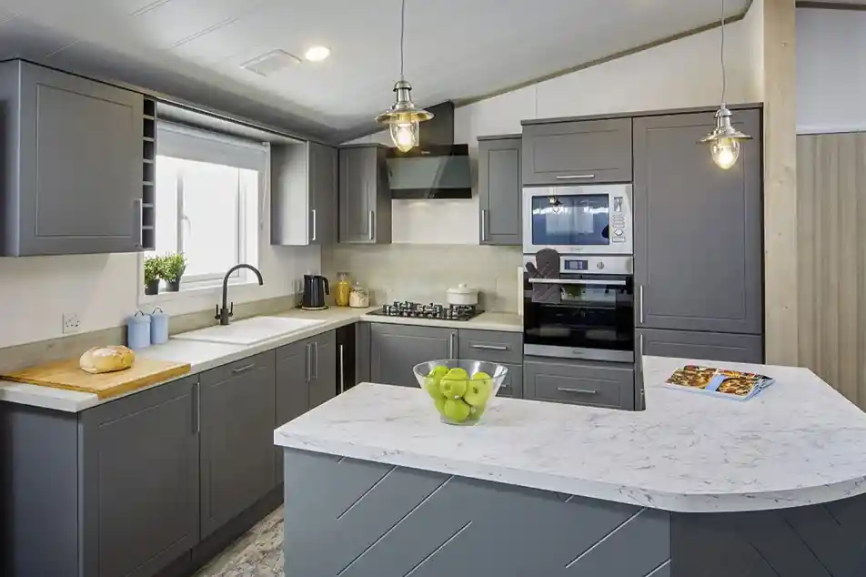Modern kitchen in the Atlas Lilac Lodge with grey cabinetry, marble-style countertops, built-in oven, and peninsula breakfast bar.