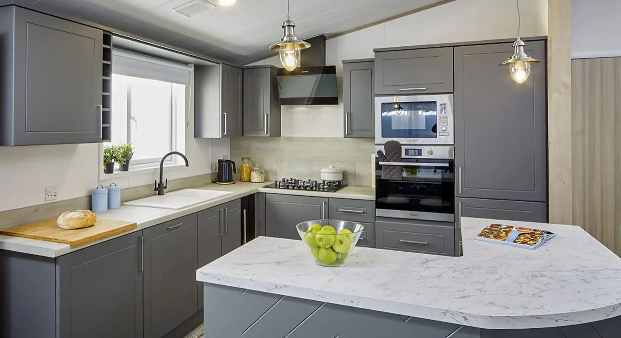Modern kitchen in the Atlas Lilac Lodge with grey cabinetry, marble-style countertops, built-in oven, and peninsula breakfast bar.