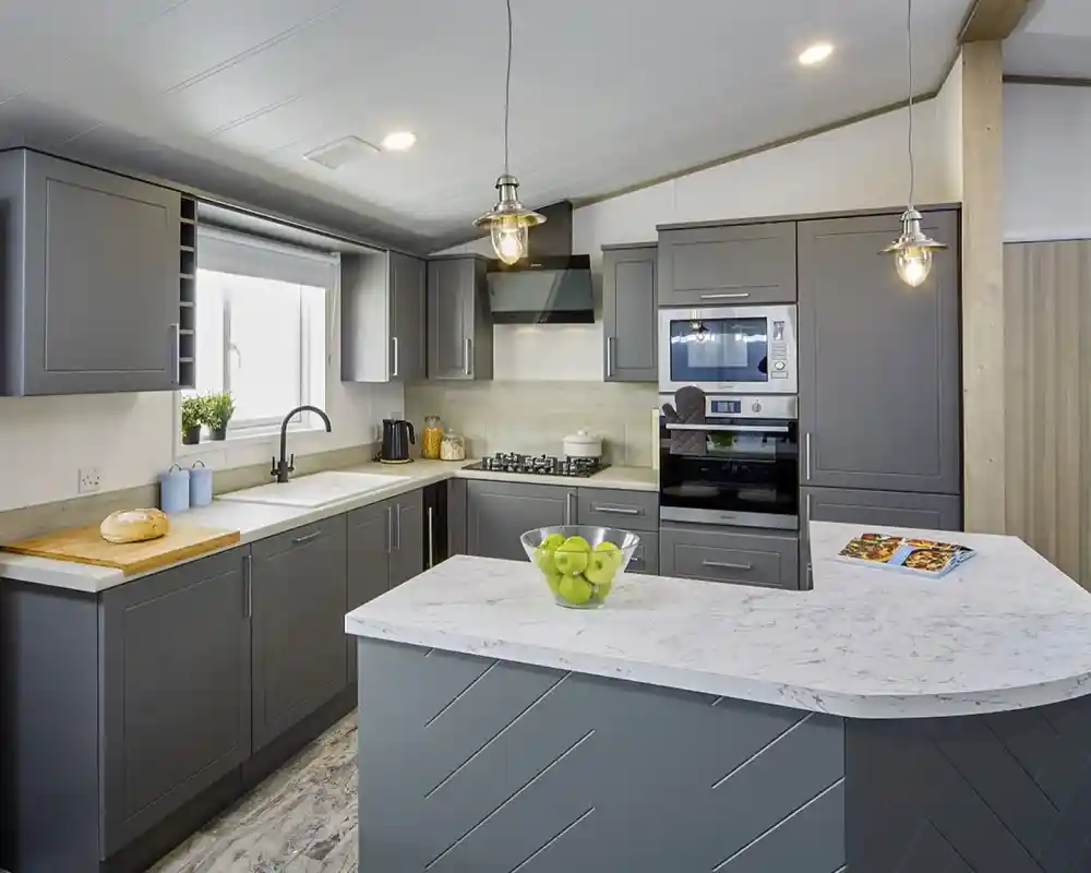 Modern kitchen in the Atlas Lilac Lodge with grey cabinetry, marble-style countertops, built-in oven, and peninsula breakfast bar.