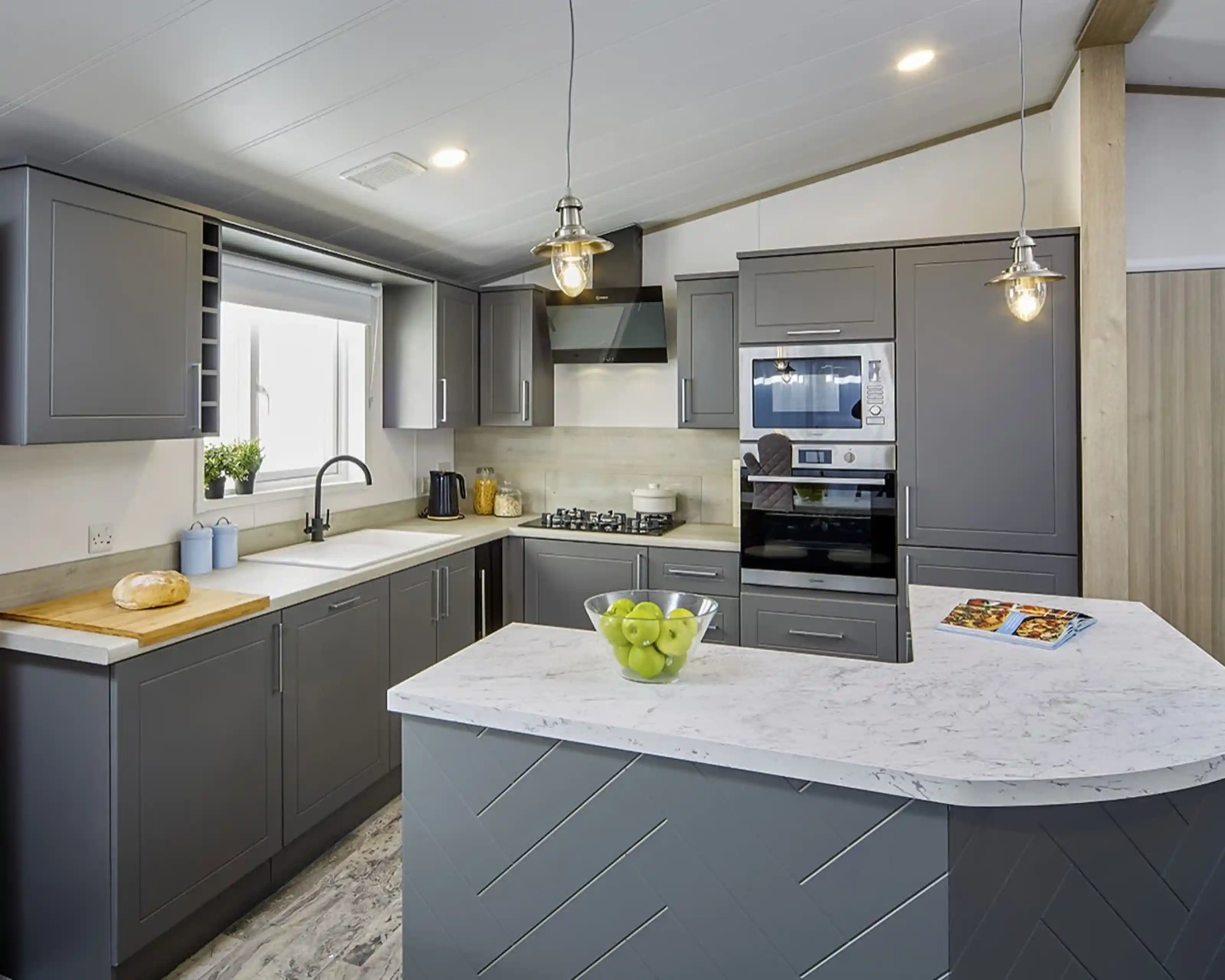 Modern kitchen in the Atlas Lilac Lodge with grey cabinetry, marble-style countertops, built-in oven, and peninsula breakfast bar.