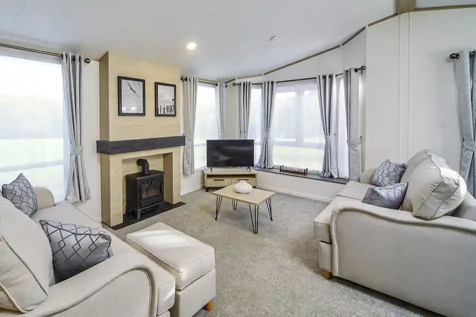 Bright lounge in the Atlas Lilac Lodge featuring large windows, neutral sofas, electric fireplace, and contemporary décor.