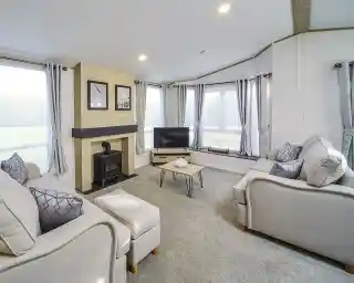 Bright lounge in the Atlas Lilac Lodge featuring large windows, neutral sofas, electric fireplace, and contemporary décor.