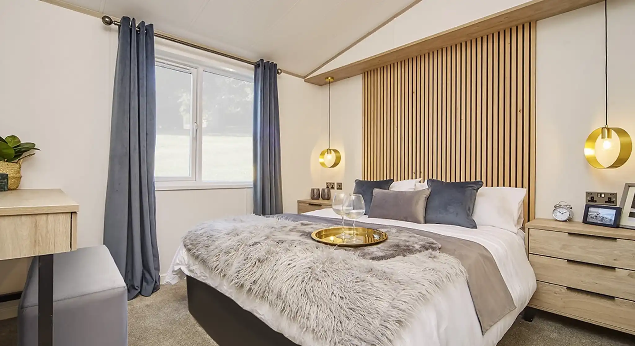 Stylish master bedroom in the Atlas Lilac Lodge with king-size bed, wooden feature headboard, pendant lighting, and plush bedding.