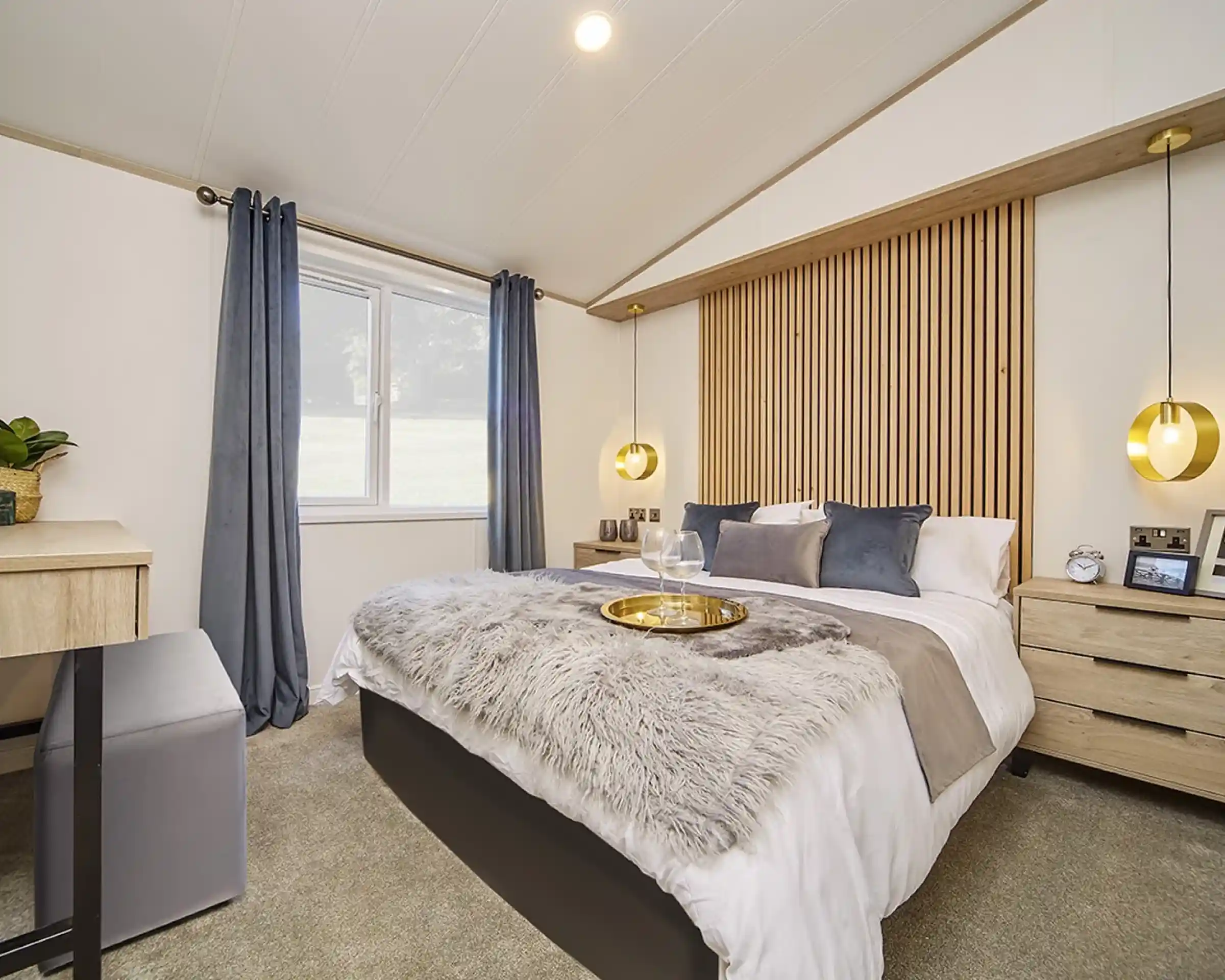 Stylish master bedroom in the Atlas Lilac Lodge with king-size bed, wooden feature headboard, pendant lighting, and plush bedding.