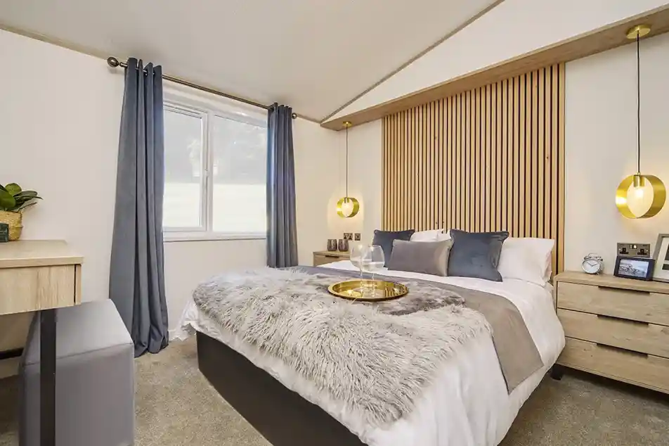 Stylish master bedroom in the Atlas Lilac Lodge with king-size bed, wooden feature headboard, pendant lighting, and plush bedding.