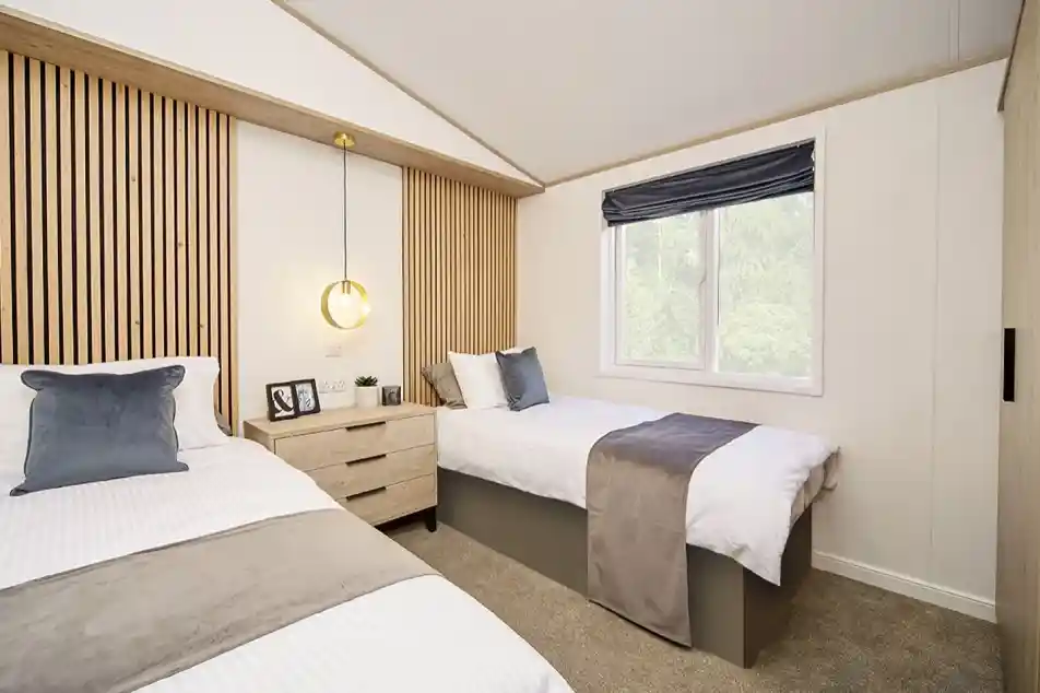 Spacious twin bedroom in the Atlas Lilac Lodge with feature wooden headboards and window for natural light.