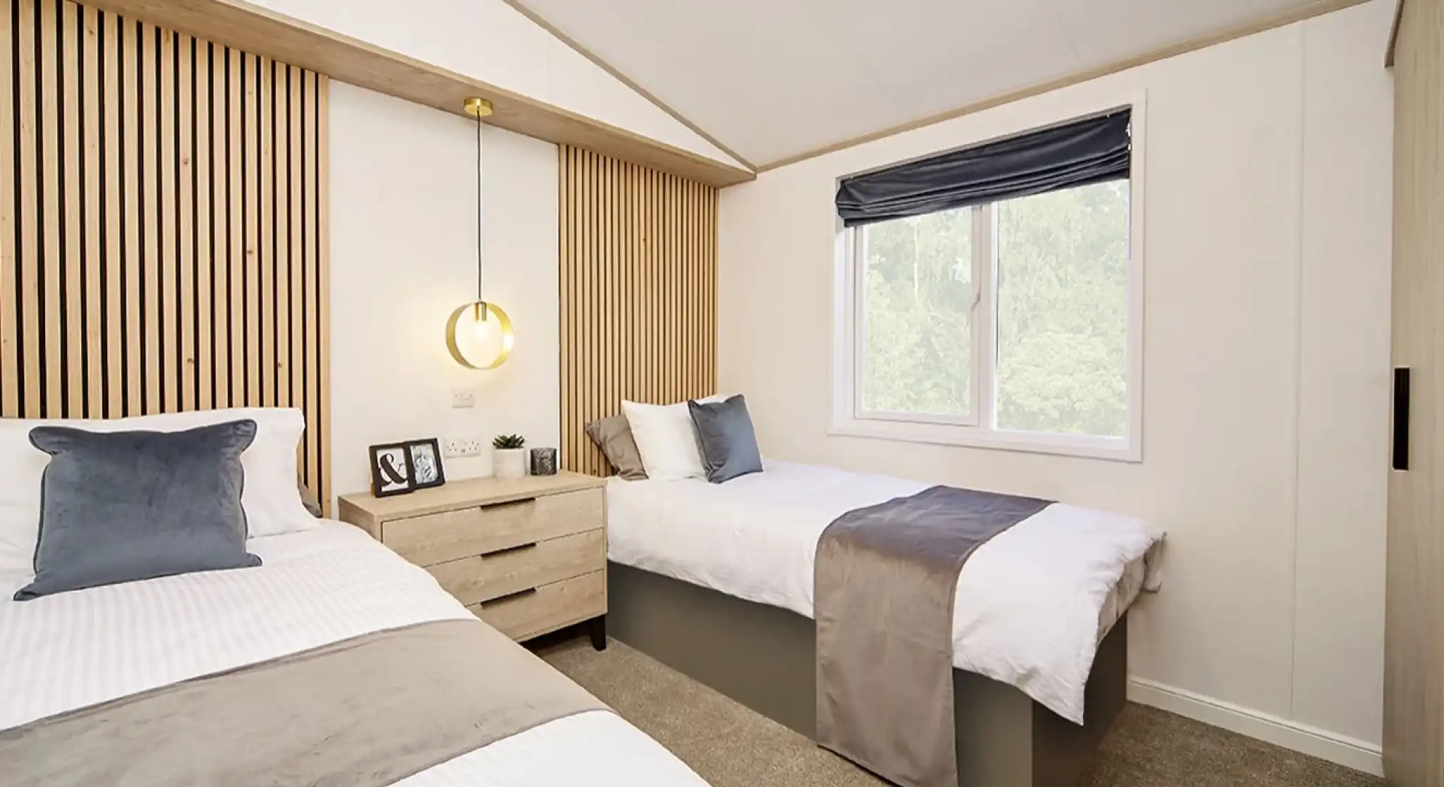 Spacious twin bedroom in the Atlas Lilac Lodge with feature wooden headboards and window for natural light.