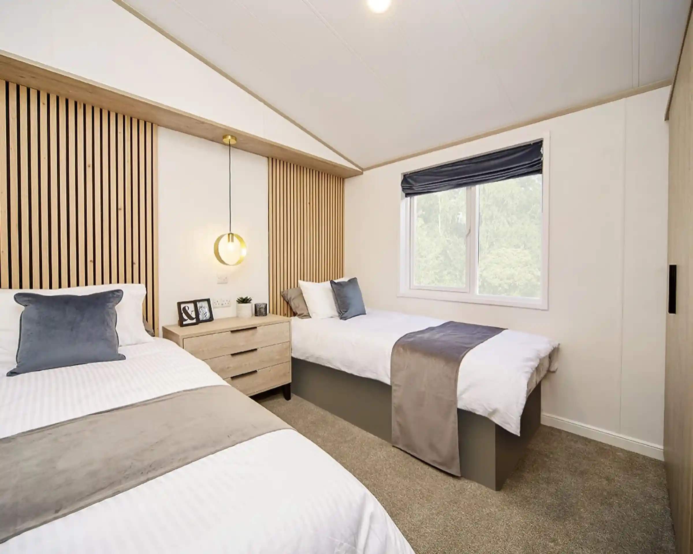 Spacious twin bedroom in the Atlas Lilac Lodge with feature wooden headboards and window for natural light.