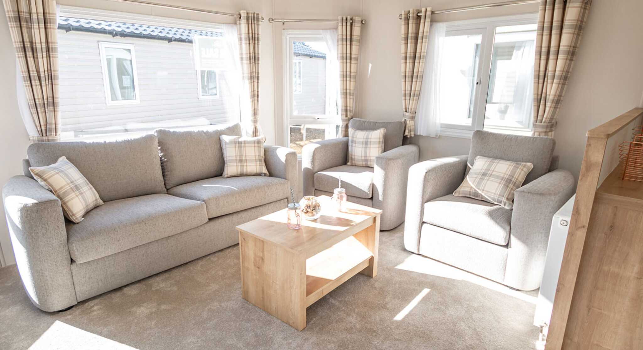 A spacious living room with a comfortable double sofas, two sofa chairs and a stylish coffee table in the centre.