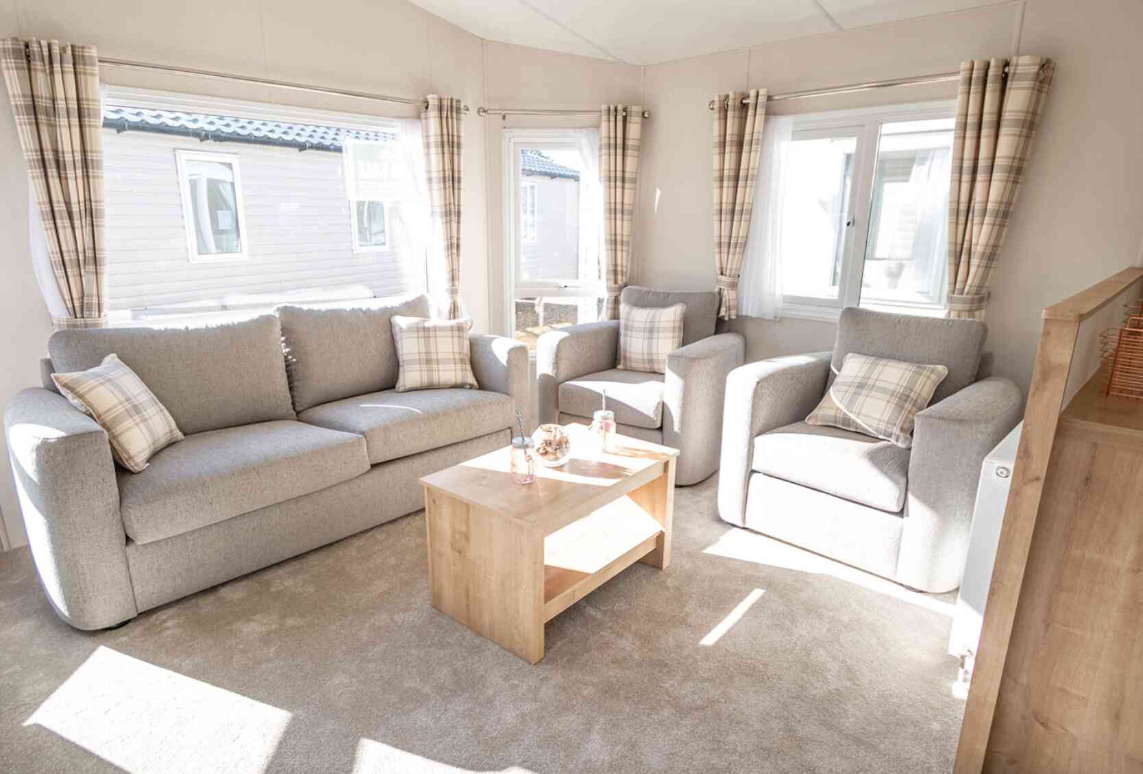 A spacious living room with a comfortable double sofas, two sofa chairs and a stylish coffee table in the centre.