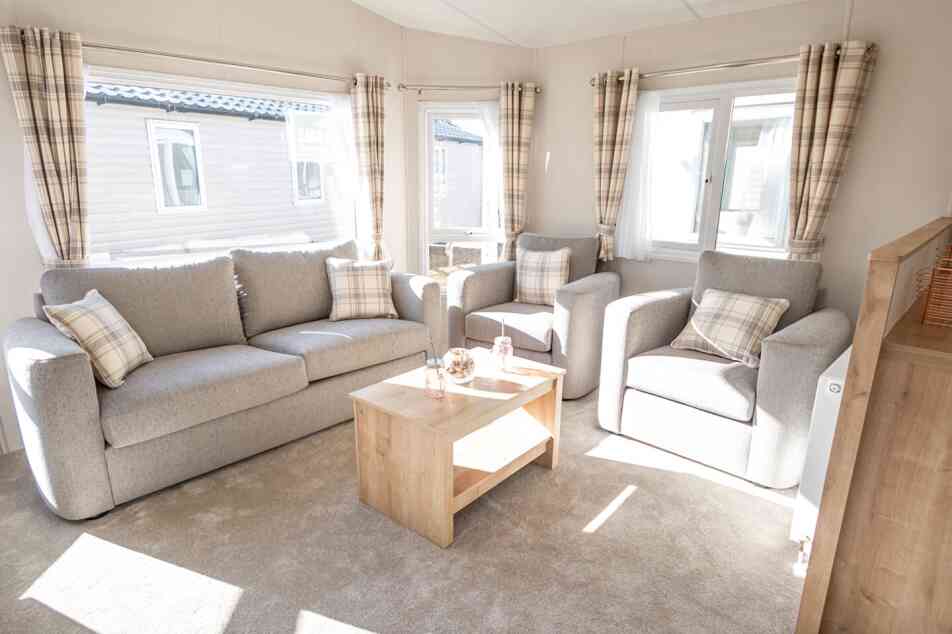 A spacious living room with a comfortable double sofas, two sofa chairs and a stylish coffee table in the centre.