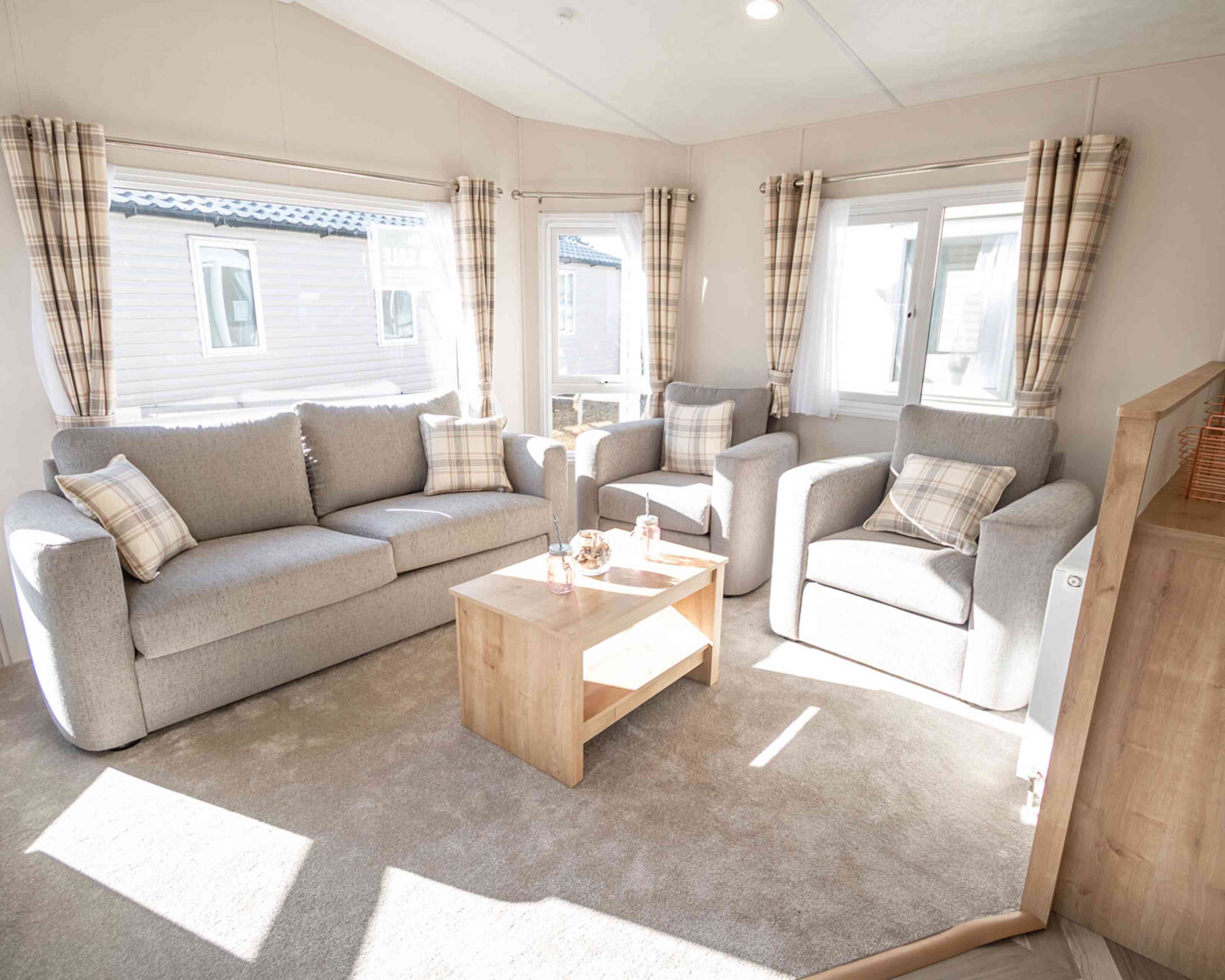 A spacious living room with a comfortable double sofas, two sofa chairs and a stylish coffee table in the centre.