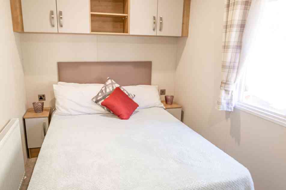 A cosy bedroom featuring a double bed, two bedside tables and overhead storage, creating a functional sleeping space.