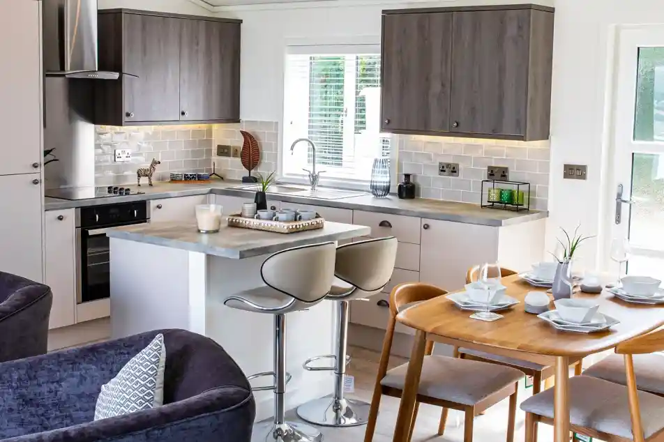 Open plan kitchen, dining, living room with light grey oak style and cream cabinetry and Scandinavian style dining table