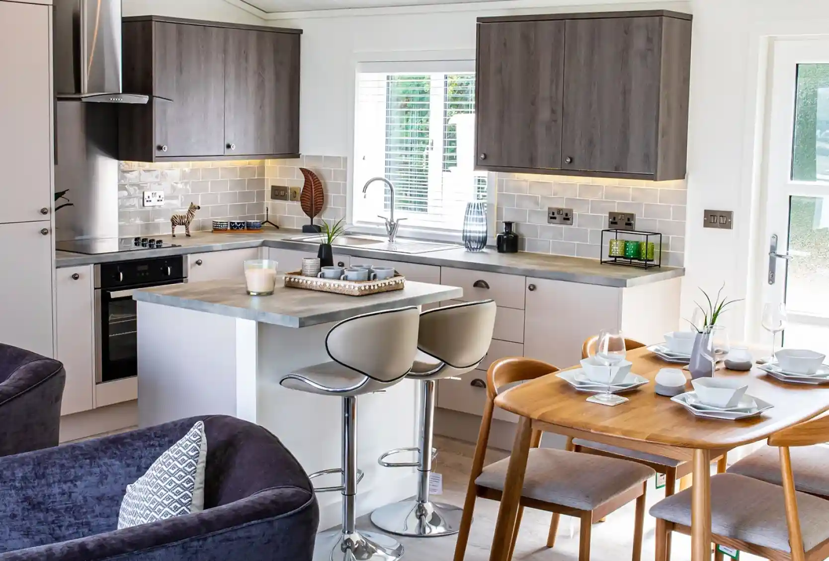 Open plan kitchen, dining, living room with light grey oak style and cream cabinetry and Scandinavian style dining table