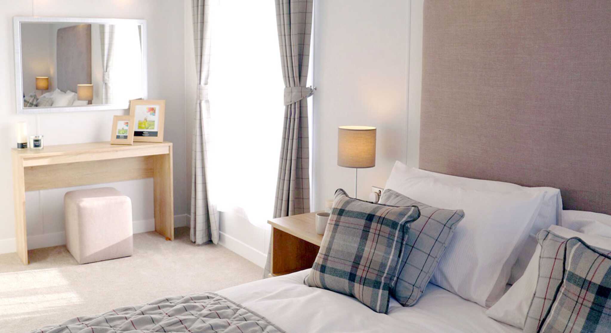 A neatly made bed featuring a white and grey plaid comforter, creating a cosy and inviting atmosphere.
