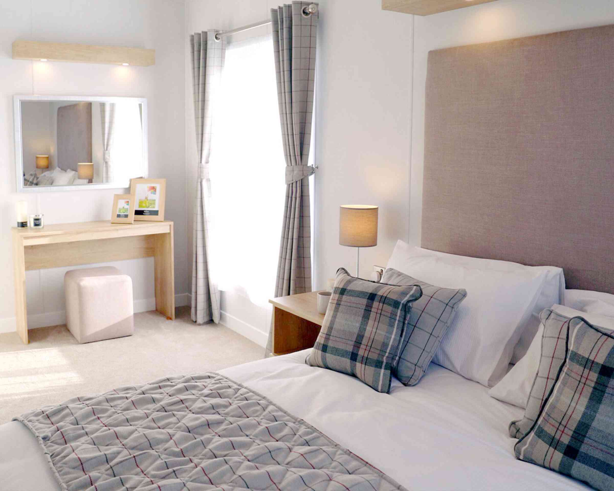 A neatly made bed featuring a white and grey plaid comforter, creating a cosy and inviting atmosphere.